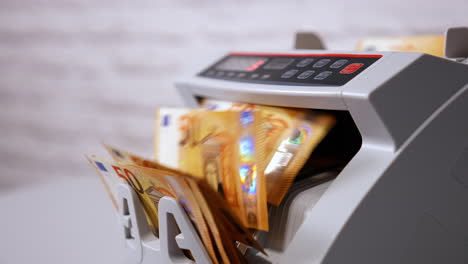 female teller putting money into currency counting machine at cash department, close up