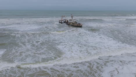 anciet ruins of shipwrecked boat on namibia's skeleton coast, aerial