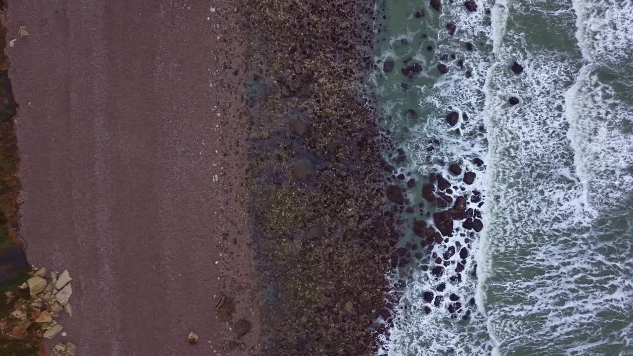 Vista verticale da drone di spiaggia rocciosa e fredde onde invernali.
