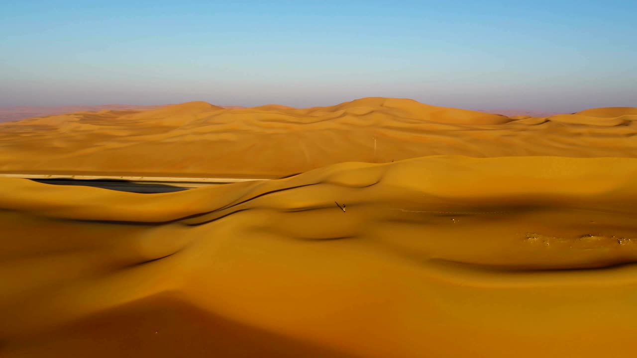 vista aérea de un hombre caminando por las dunas durante la puesta de sol, u.a.e.