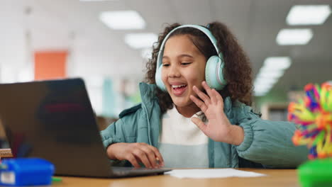 a young girl learning online with a laptop and headphones