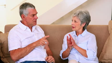 senior couple sitting on couch having an argument