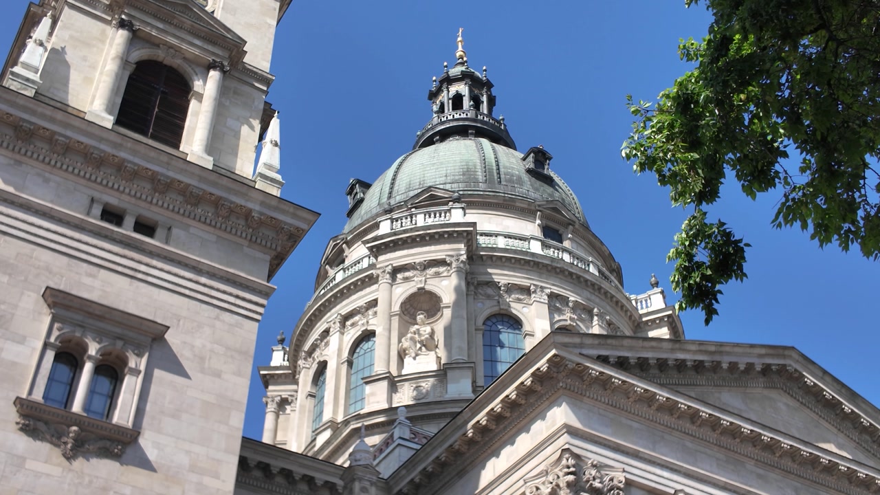 Dome of St. Stephen’s Basilica, framed by tree leaves, highlighting its ornate architecture and historic elegance.