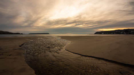 Un-Lapso-De-Tiempo-De-Un-Arroyo-Que-Se-Dirige-Al-Mar-Al-Atardecer-En-La-Costa-De-Kapiti-En-Nueva-Zelanda