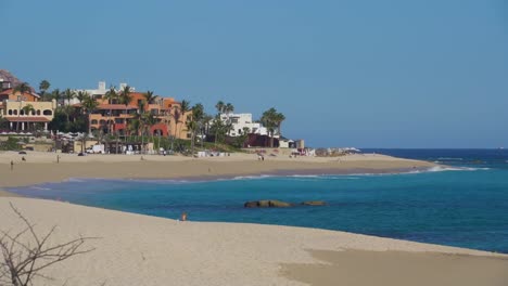 colorful buildings next to ocean with palm trees , sand and gentle waves