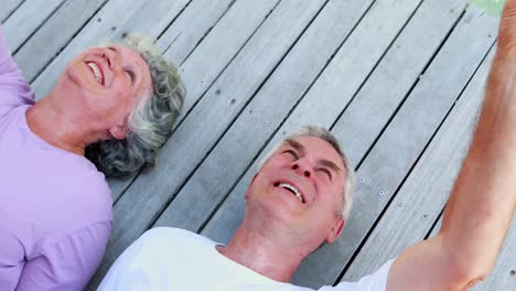 Senior-couple-lying-on-wooden-plank-4k
