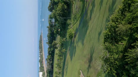 tiro vertical del campo de golf de playa dorada con veleros en la playa de puerto plata, república dominicana