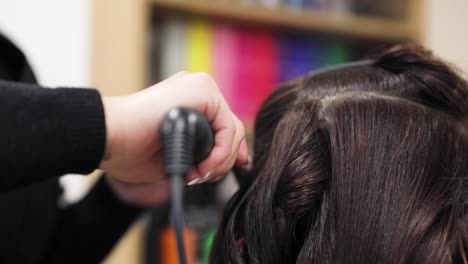 hairstylist making hair-do with hair iron