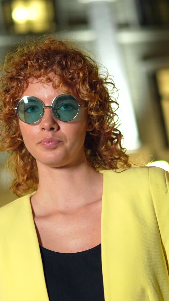 Woman with curly hair and round sunglasses