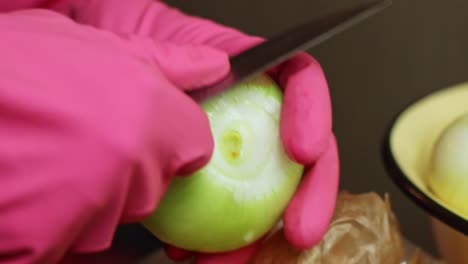 peeling onion skin wearing latex rubber gloves closeup