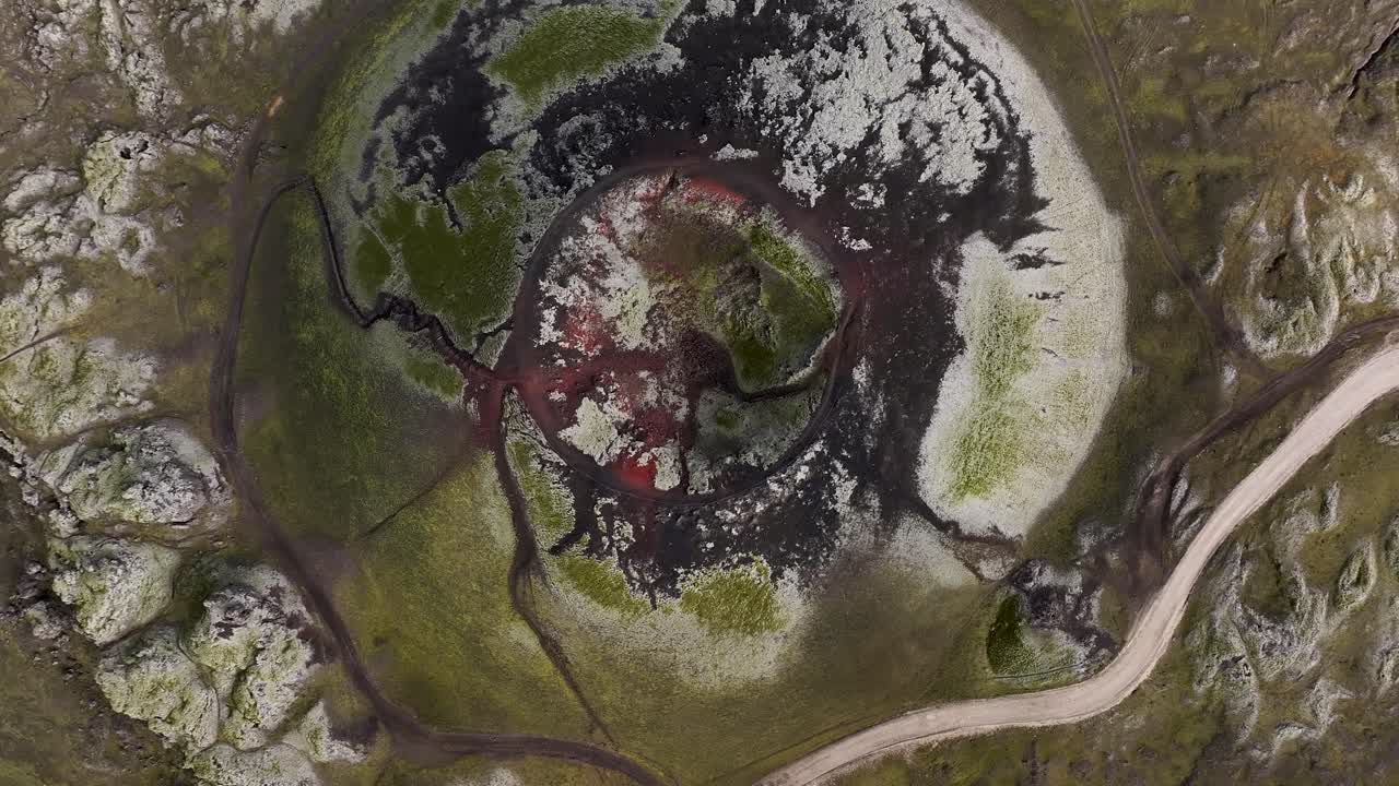 Aerial top down shot of stutur crater in Icelandic highlands. Rising shot. Street with parking cars on cloudy Day in fall