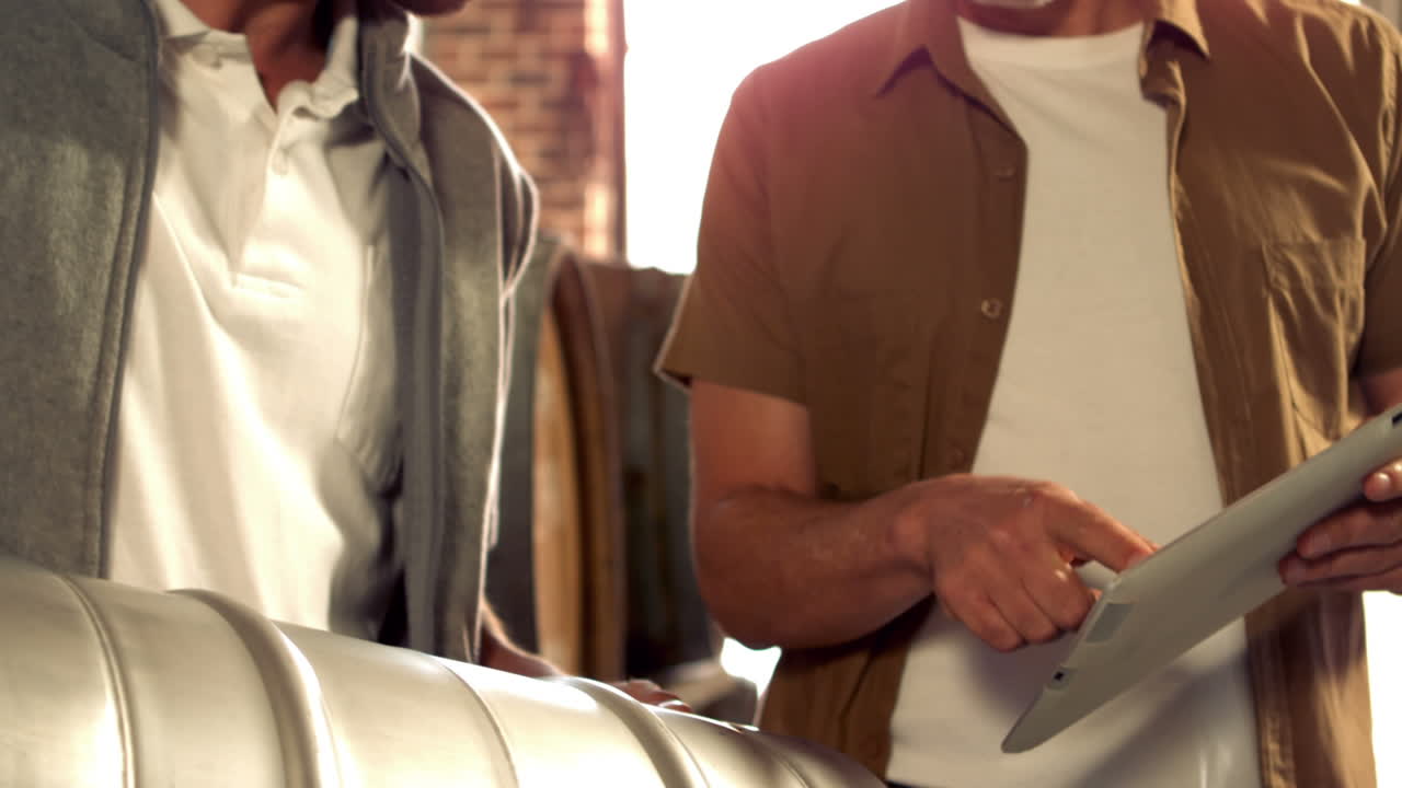 trabajadores de la cervecería sosteniendo un barril y comprobando una tableta