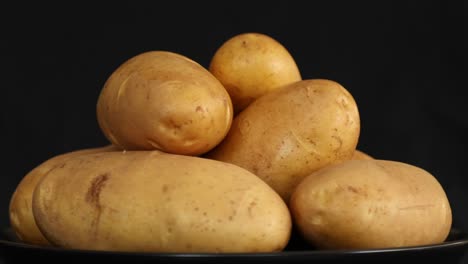 raw potatoes spinning and rotating isolated on black background