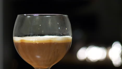 Delicious-Irish-coffee-drink-prepared-on-bar-counter,-close-shot-on-black-bokeh-background