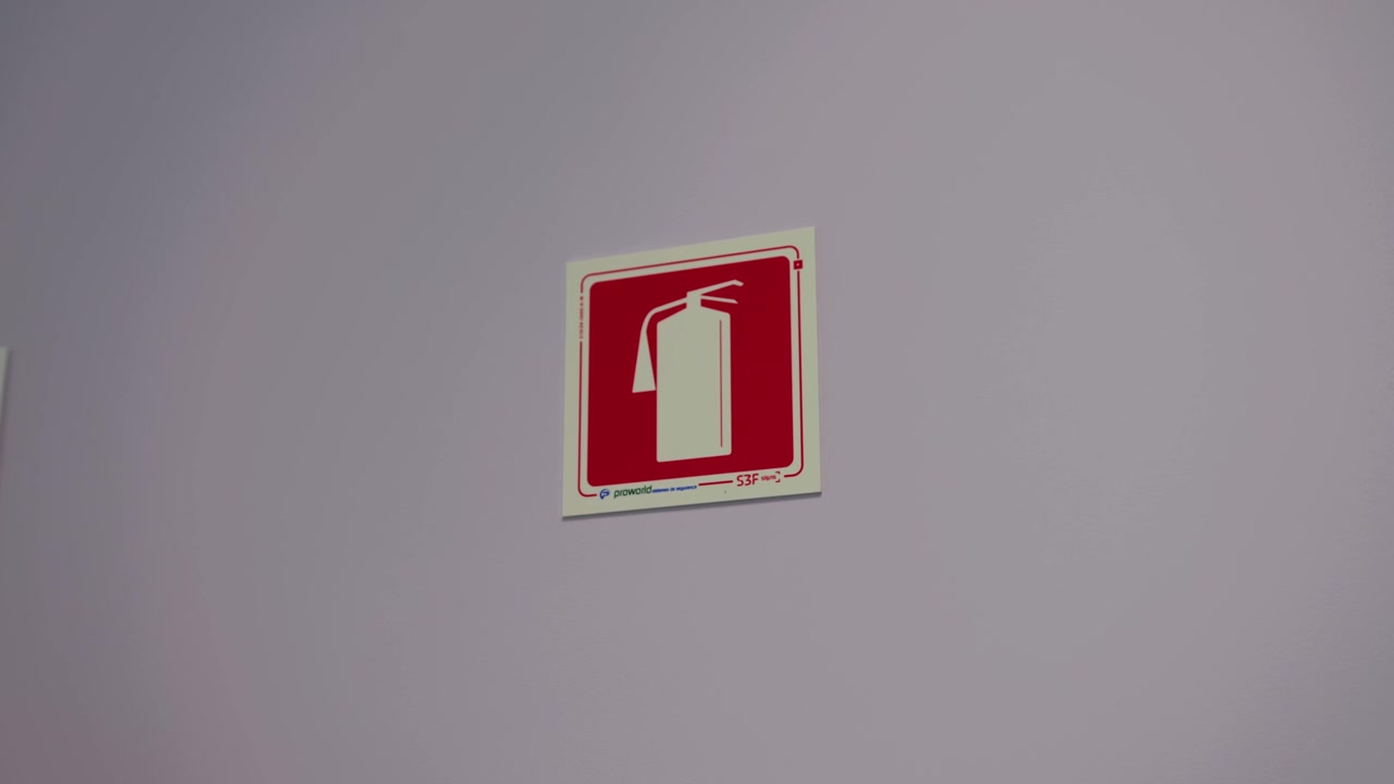 Red and white fire extinguisher symbol sign mounted on plain grey interior wall