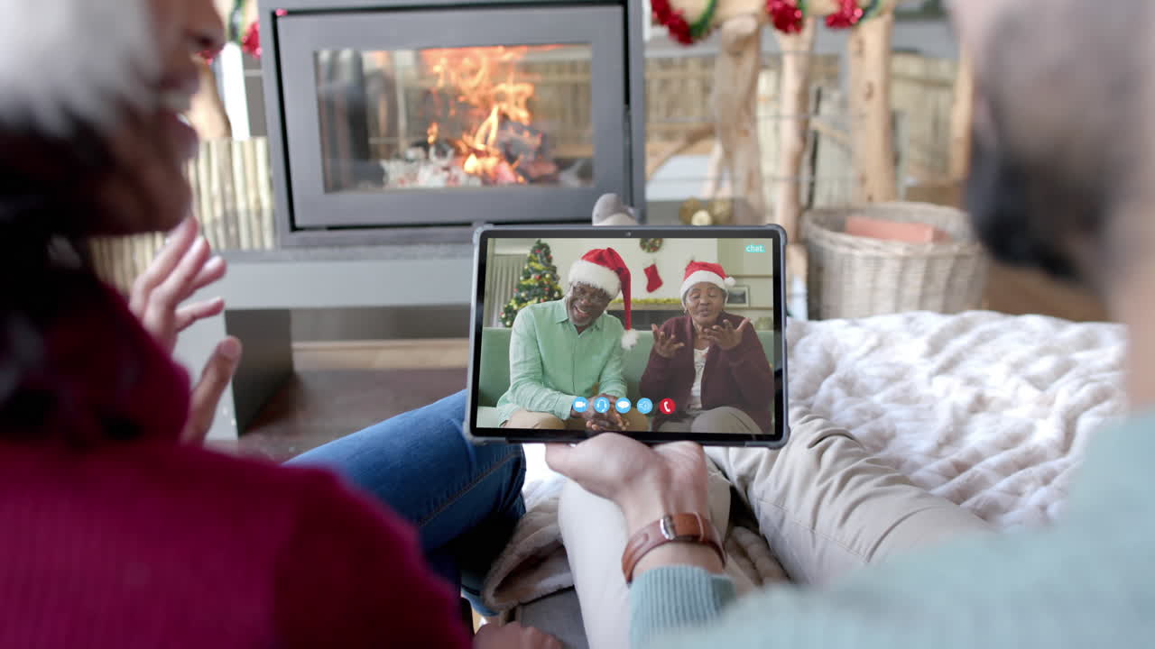 Coppia felice e diversificata e genitori anziani in videochiamata di Natale su tablet, al rallentatore