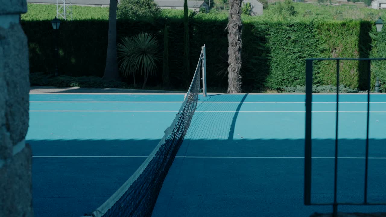 una cancha de tenis vacía con una red negra en una superficie azul brillante