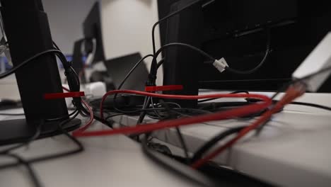 close up behind computer monitor stand of cables, ethernet, power leads