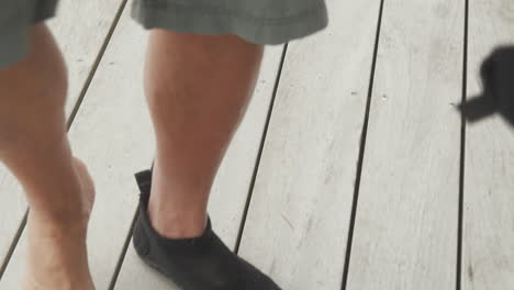 persona que se pone zapatos de agua antes de una aventura en la playa