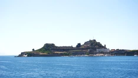 view of corfu island from a sailing ferry, showing buildings and a cross on it