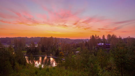 colorful and vibrant sunset sky over countryside landscape with vacation house and a pond surrounded by lush green trees