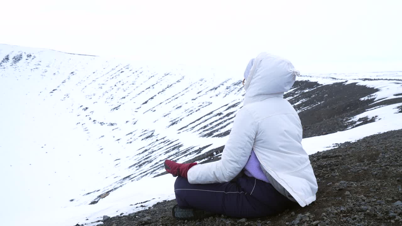 Nainen lumisessa maisemassa meditoimassa