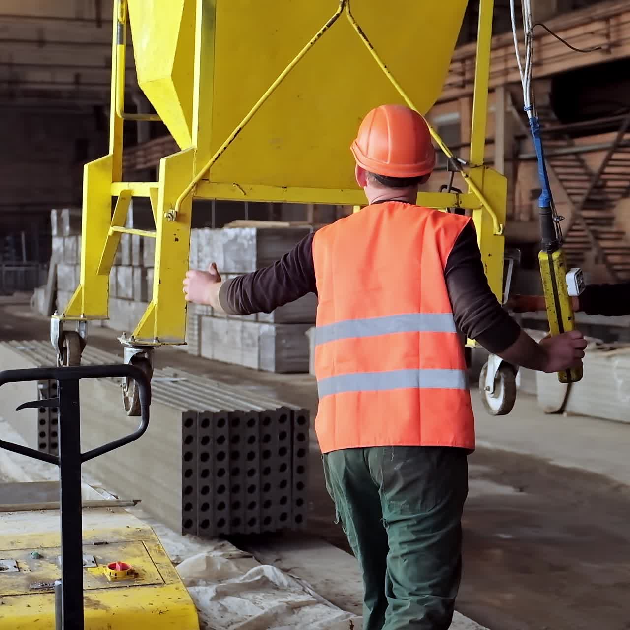 Workers on the concrete plant. Plant for the creation of reinforced concrete slabs. Employees in hard hat work inside manufacturing. Heavy industry concept.