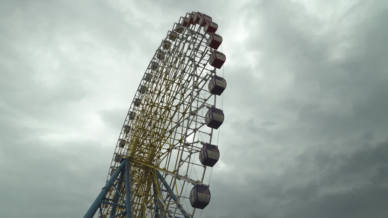 колесо обозрения, выстрел в облака и облачное небо. теплые цвета, дневной свет.