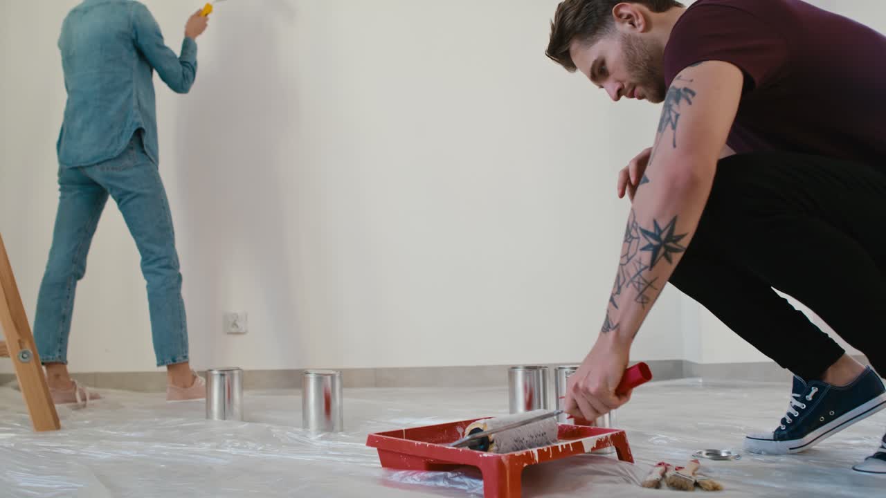 video de seguimiento de una pareja caucásica pintando la pared en una casa nueva
