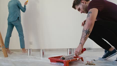 tracking video of caucasian couple painting wall in new house