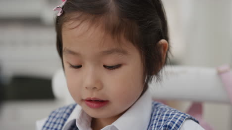 cute little asian girl eating breakfast enjoying cereal in kitchen getting ready wearing school uniform 4k