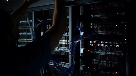 a technician working on server racks in a dark data center