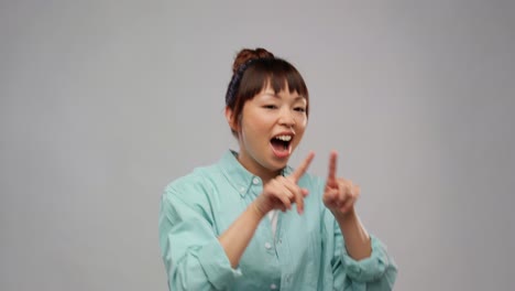 Mujer-Asiática-Feliz-Bailando-Sobre-Fondo-Gris.-Concepto-De-Felicidad-Y-Personas.-Mujer-Asiática-Feliz-Y-Sonriente-Bailando-Sobre-Fondo-Gris.