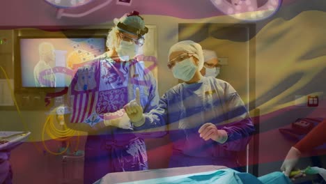 Animation-of-spanish-national-flag-waving-over-surgeons-discussing-in-operating-room-during-surgery