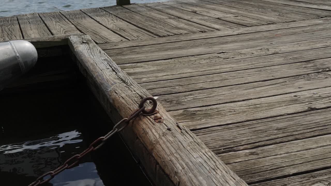 wooden boat dock on lake with pontoon boat chained tied off