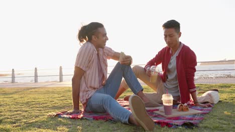 feliz pareja masculina gay diversa haciendo picnic en el paseo marítimo, cámara lenta