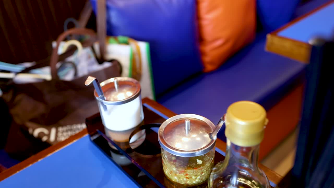 Mano che prende fiocchi di peperoncino dal porta-condimenti sul tavolo del ristorante