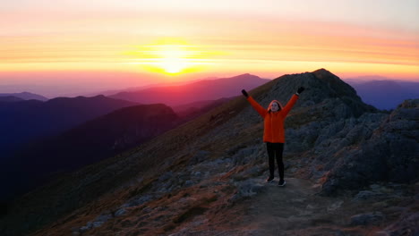 woman on mountain ridge at sunset