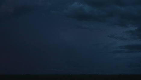 bright flashes of lightning fill the dark sky under an impressive storm cloud