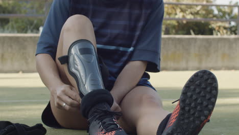 Primer-Plano-De-Una-Jugadora-De-Fútbol-Femenina-Irreconocible-Poniéndose-Soporte-Para-El-Tobillo