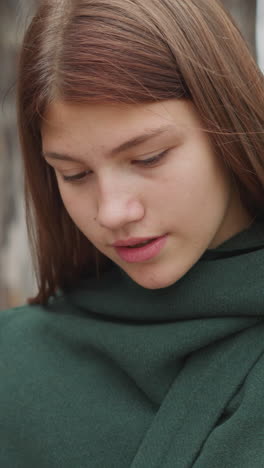 girl in medieval clothes reads note on piece of parchment standing near wooden fence. young female receives secret message closeup on blurred background