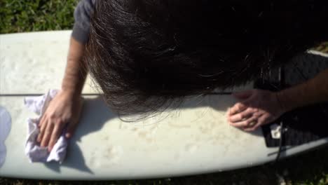 Aerial-view-of-a-surfer-cleaning-the-board-on-the-grass