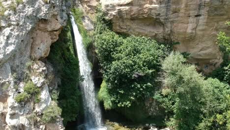 aerial views of a waterfall with a cave and an old building in catalonia, spain