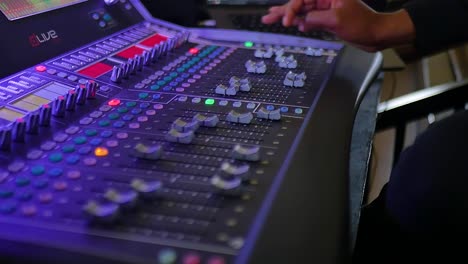 a skilled hand delicately manipulating the controls and buttons on an audio mixer