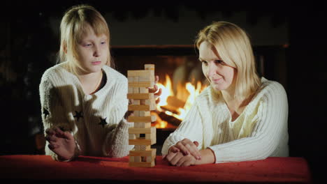 mutter und tochter spielen zusammen ein brettspiel, bei dem sie blöcke aus dem turm ziehen müssen