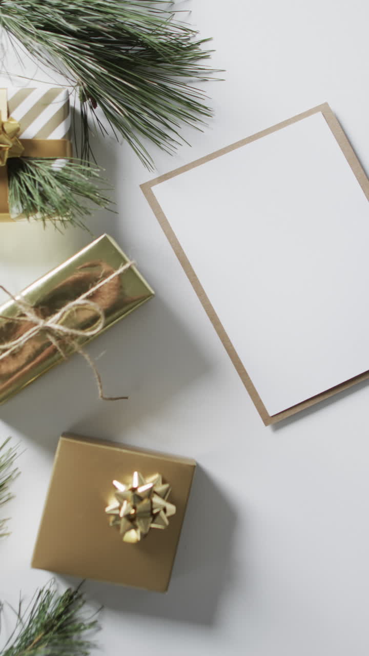 Vertical video of christmas presents, decorations and paper with copy space on white background