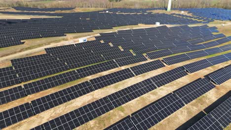 Aerial-shot-of-large-power-plant-of-solar-panels-in-Electrum-solar-park-in-a-vast-field-on-a-sunny-day-in-Taurage,-Lithuania