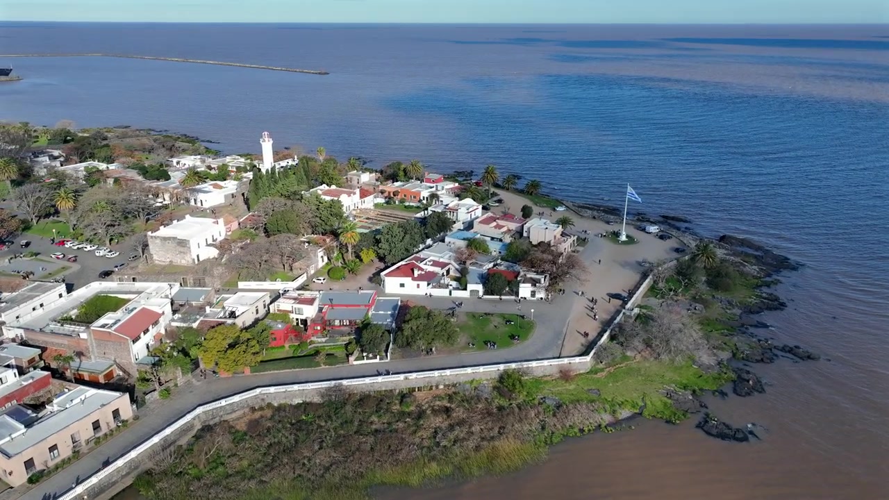 Colonia del Sacramento aerial descend over Bastión de San Pedro fortification on the rocky waterfront with lighthouse and historic buildings