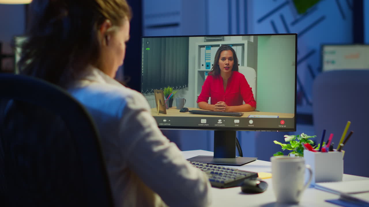 Manager talking with coworker during video conference at midnight