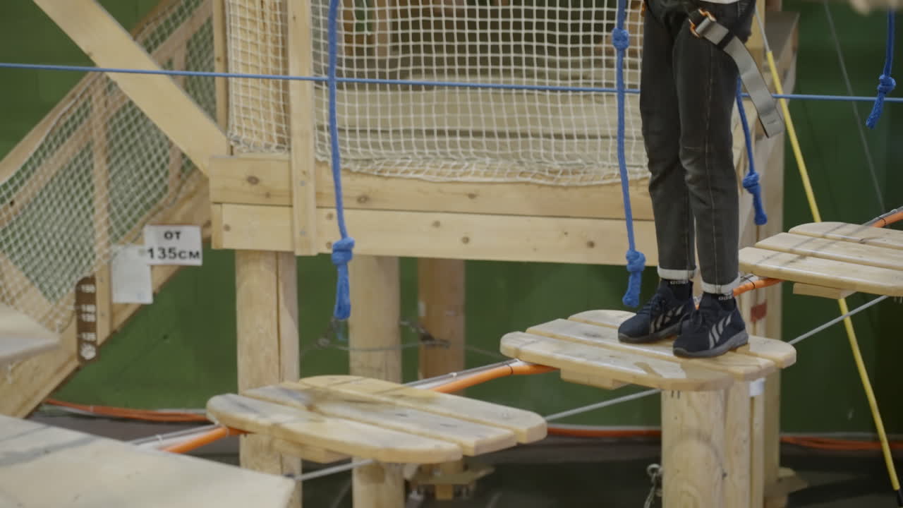Child navigating an indoor rope course at an adventure park
